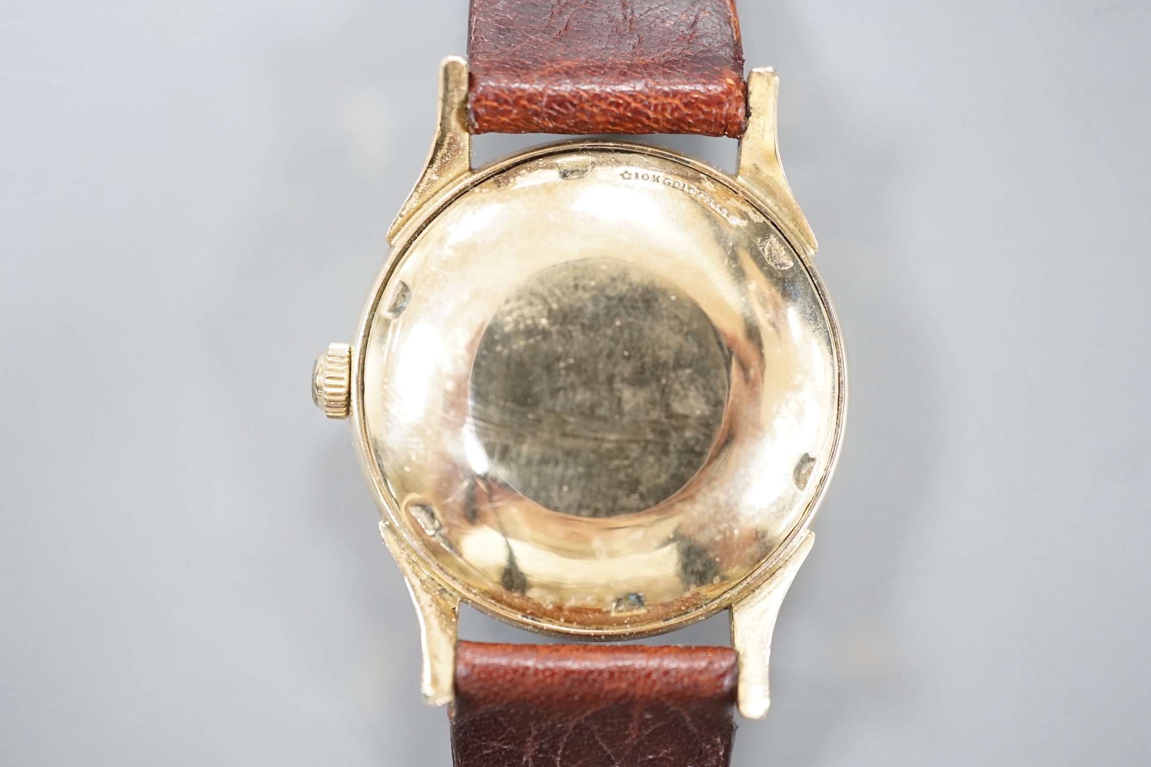 A gentleman's 10k gold filled Longines automatic wrist watch, the 'quartered' dial with Roman and dot markers, on a brown leather strap, case diameter 33mm.